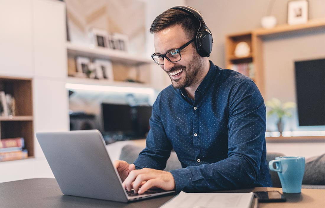 Man smiling while using a laptop computer in his home office.