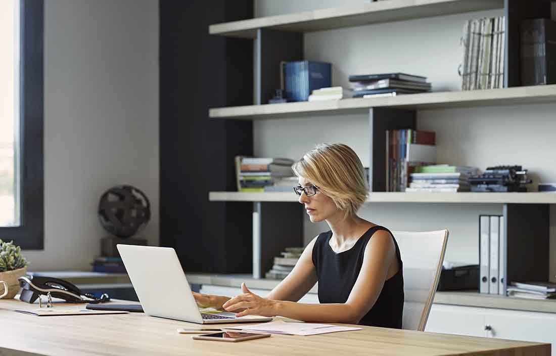 Business professional sitting in an office using a high-end laptop.