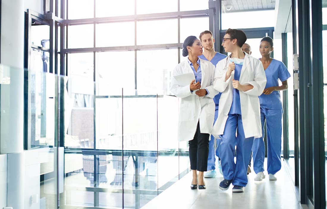 Doctors walking in a hallway talking with one another.