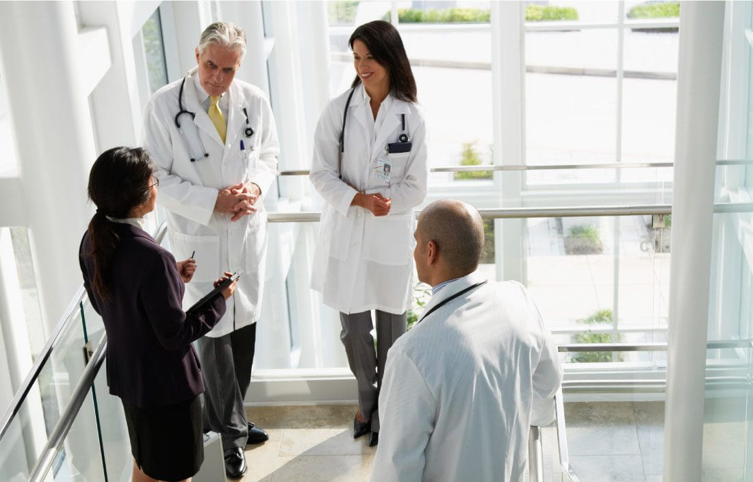 Doctors standing and talking together on a stairway.