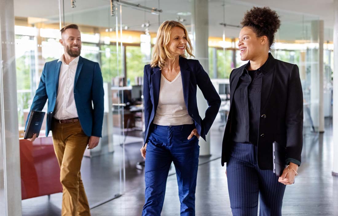 Three business professionals walking and discussing how to design and implement a finance digital transformation strategy