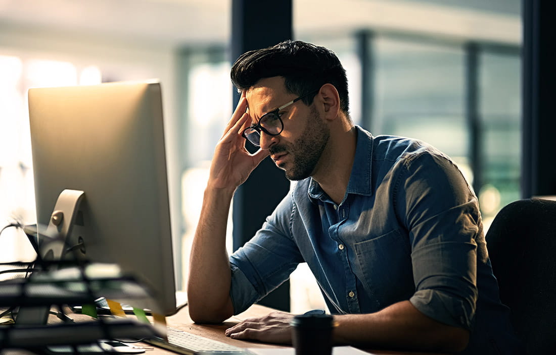 A man frustrated while looking at his desktop computer. 